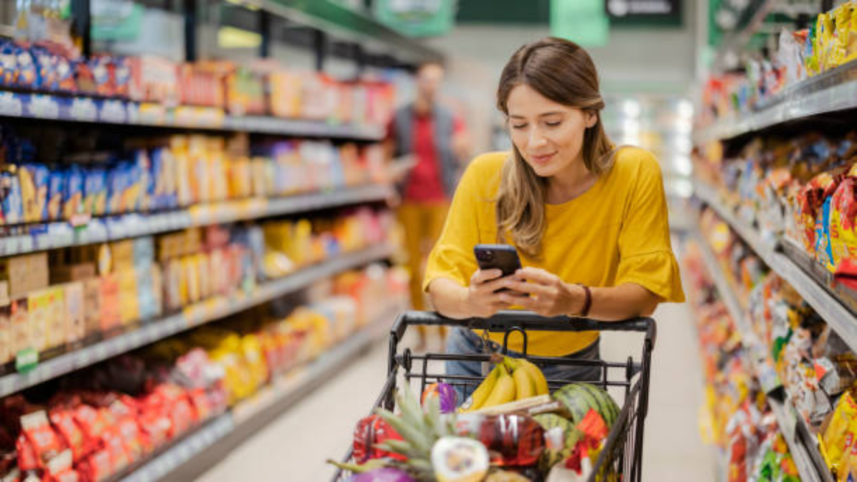Female customer shopping with smartphone checklist, taking products from shelf at the shop